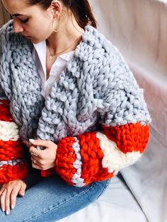 a woman is sitting on a couch wearing a knitted sweater