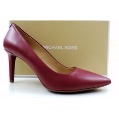 a pair of red high heeled shoes next to a box with michael kors logo on it