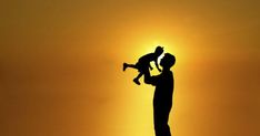 the silhouette of a man holding a child in his arms as the sun goes down