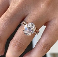 a woman's hand with a ring on her finger and an oval shaped diamond in the middle