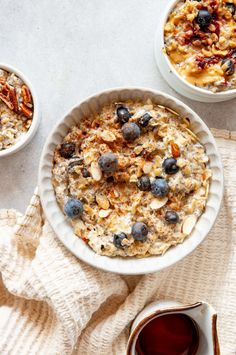 two bowls of oatmeal with blueberries and pecans on the side