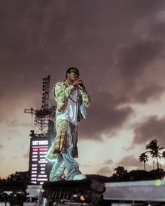 a man standing on top of a car in front of a tall building with a sky background