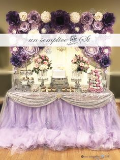 a table with purple and white flowers on it is set up for a wedding reception