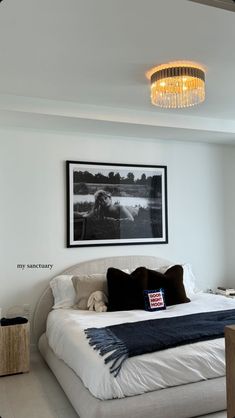 a bedroom with a large bed and a chandelier hanging from the ceiling above it