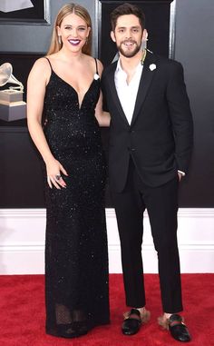 a man and woman in formal wear on the red carpet at an awards event, posing for