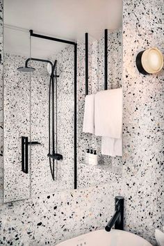 a bathroom with black and white speckles on the walls, shower head, and bathtub