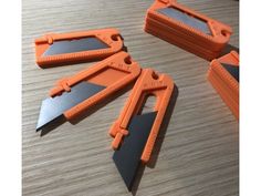 four orange and black blades on top of a wooden table next to a pair of scissors