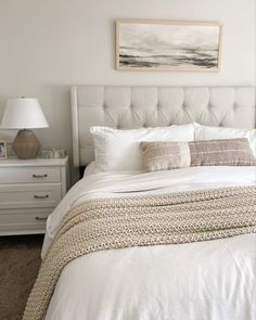 a bed with white linens and pillows in a bedroom