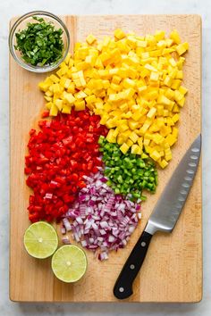 chopped up vegetables on a cutting board next to a knife and bowl with limes