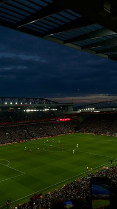 a soccer field at night with the lights on and fans in the stands looking on