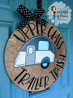 a wooden sign that says upper class trailer trash hanging on a blue door with polka dot ribbon