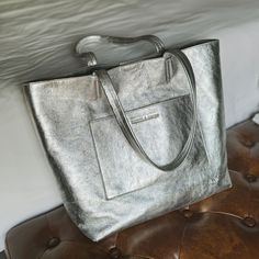 This exquisite Silver Everyday Tote is carefully crafted from luxuriously textured silver leather, accompanied with two shoulder straps. This timeless piece features a charcoal gray antigoccia coating interior lining and two interior zipper pocket for extra security, with an additional exterior zipper pocket. This everyday tote bag fits a 14" laptop, this handbag is crafted with Italian finesse and is the perfect everyday accessory. Style Quizzes, Nickel And Suede, Everyday Tote Bag, Luxe Jewelry, Everyday Tote, Everyday Accessories, Birthstone Earring, Metallic Leather, Leather Earrings