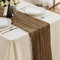 the table is set with white plates and silverware, along with an elegant centerpiece