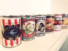 a row of cans sitting on top of a white counter next to each other in front of a wall