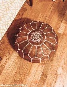 a brown ottoman sitting on top of a hard wood floor next to a white rug