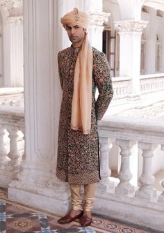 a man standing in front of a building wearing a turban and holding his hand on his hip