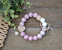 two bracelets with pink and white beads are sitting next to a potted plant