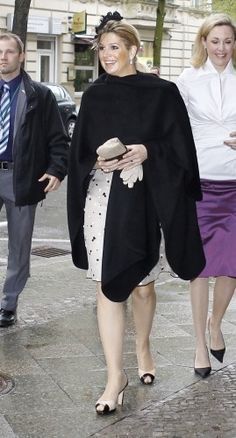 two women walking down the street with one woman in a black coat and purple skirt