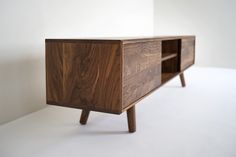 the sideboard is made out of wood and has two drawers on one end, and an open drawer on the other