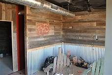 the inside of a building with wood paneling and metal pipes on the ceiling, next to an open garage door