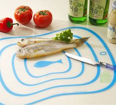 there is a fish on the cutting board next to some tomatoes and other food items