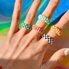 a woman's hand with four different rings on her fingers and one is holding the other