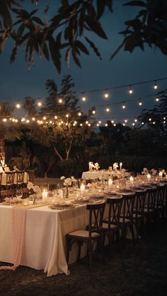 a long table is set up with candles and place settings for an outdoor dinner party