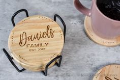 two personalized wooden coasters sitting next to a cup of coffee and saucer