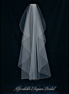 the back of a wedding veil with an embroidered flower on it, against a black background