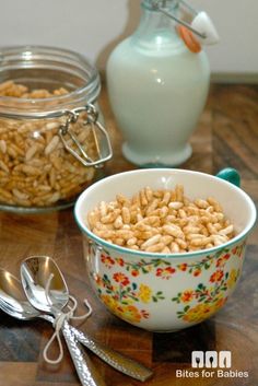 two bowls filled with cereal sitting on top of a wooden table next to spoons