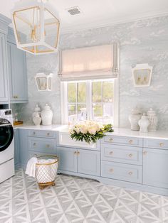 a white and blue kitchen with gold accents on the windowsills, marble counter tops and cabinets