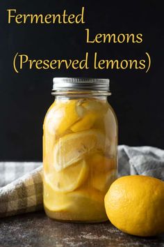 a jar filled with lemons next to a sliced lemon