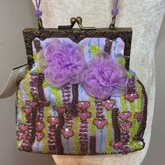 Beautiful Beaded Lilac Dress Bag By Tahari. Adorned With Chiffon Flowers On Both Sides. Lilac Beaded Straps. Brass Colored Hardware. Metallic Gold And Copper Colored Beads As Well As Beads In Hues Of Blue, Chartreuse And Pink Complete The Color Scheme. There Are A Couple Of Tiny Loose Threads Here And There But Hardly Noticeable And That Is The Way The Purse Came. Its Missing Some Blue Beads Near Side But A Again, Not Noticeable When Worn. Never Been Worn & Otherwise In Excellent Condition. Elegant Beaded Bags For Spring, Embellished Bags For Formal Occasions In Summer, Embellished Bags For Formal Summer Events, Purple Embroidered Party Bag, Summer Formal Embellished Bags, Embellished Evening Bag For Summer, Embellished Evening Bags For Summer, Summer Evening Bag With Beads, Spring Evening Embellished Bags