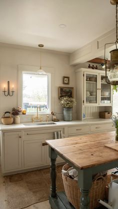 a kitchen with a wooden table in the middle of it and lots of white cabinets