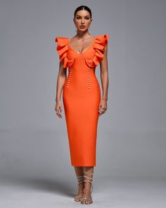 a woman in an orange dress poses for the camera with her hands on her hips