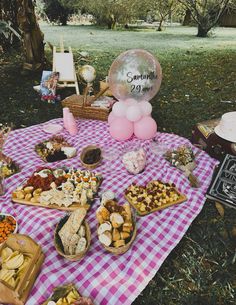 an outdoor picnic with food and balloons