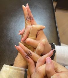 three people are holding their hands together with tattoos on their fingers and the other hand is pointing up