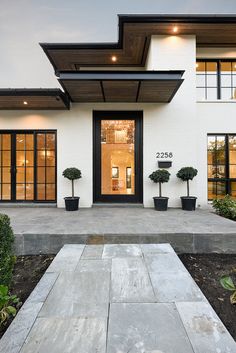 the front entrance to a modern home with black and white trimmings on the windows