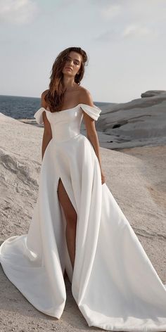 a woman in a white dress posing on the beach