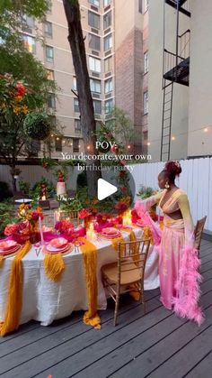 a woman standing next to a table covered in pink and yellow decorations