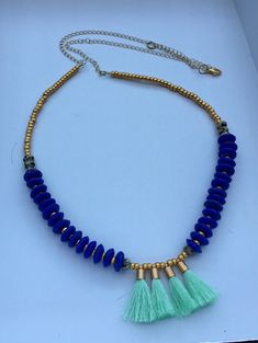 a necklace with blue beads and green tassels