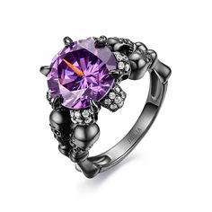 Inspired from Halloween, crafted in black tone sterling silver, this cool skull ring features its four skulls on the band. They will show a unique look on your finger. The hidden skulls under the mount will shine brilliantly with every movement of your finger. Moreover, the ring is set with a 9mm round-cut amethyst purple center stone, which makes the ring a more feminine piece. If you are looking for unique skull jewelry, then take this masterpiece. It won't disappoint you!Carat Weight: 8.5 ctStone Size: 11 mmStone Type: Jeulia® StoneNumber of Stones: 1 Stone Color: Amethyst PurpleStone Shape: RoundCarat Weight: 0.56 ctStone Size: 1.1,1 mmStone Type: Jeulia® StoneNumber of Stones: 56 Stone Color: Diamond WhiteStone Shape: RoundWeight: 7.73 gWidth: 13.2 mmHeight: 8.74 mmThickness: 2.74 mmM Black Skull Print Ring, Black Skull Rings Punk Style, Punk Style Black Skull Rings, Gothic Black Rings With Skull Print, Black Skull Rings In Punk Style, Halloween Black Skull Ring, Black Skull Ring For Halloween, Halloween Black Skull Print Rings, Black Skull Print Rings For Halloween