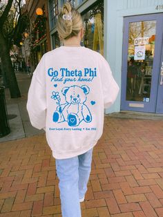 a woman is walking down the street with a teddy bear on her jacket and jeans