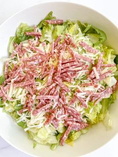 a white bowl filled with lots of lettuce and meat on top of it