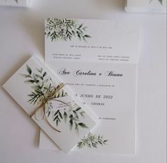 the wedding stationery is decorated with greenery