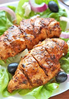 two pieces of chicken on a plate with lettuce and blueberries