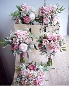 three bouquets of flowers sitting on top of a wooden table next to each other