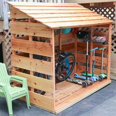 a small wooden shed with a bicycle and scooter in the garage area next to a green lawn chair