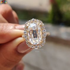 a close up of a person holding a ring with an oval cut diamond in it