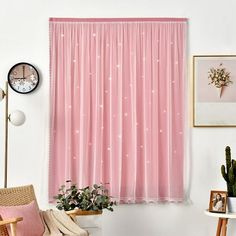 a living room filled with furniture and a large window covered in pink drapes next to a potted plant